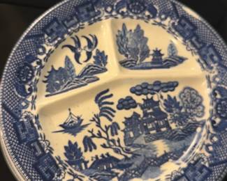 Blue Willow Japan Divided Plate — This Blue Willow divided plate features classic blue and white scenic design, crafted in Japan. The plate is made of ceramic with three compartments, ideal for serving multiple dishes or appetizers. Measuring approximately 10 inches in diameter, it offers practical use with charming vintage appeal. The piece is in good condition with some minor surface wear consistent with age and use. Marked Made in Japan on the back, this plate reflects mid-20th century export dinnerware style.