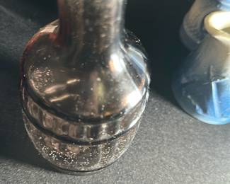 Vintage Glass Bottle — This vintage black glass bottle features a distinct rounded, ribbed design reminiscent of early 20th century glassware. Its compact size and textured surface suggest it may have been used for medicinal or decorative purposes. Measuring approximately 4.5 inches in height and 2.5 inches in width, this bottle is a charming collectible for vintage glass enthusiasts. The bottle shows signs of age with some surface speckling and minor wear but is structurally intact. It makes a great addition to any collection of antique or vintage bottles.