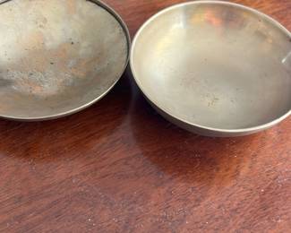 Vintage Small Metal Trinket Box — This vintage small metal trinket box features a simple, round design with a removable lid. The box has a smooth matte finish with subtle patina indicative of age, adding character to the piece. Measuring approximately 2.5 inches in diameter and 1 inch in height, it is perfect for storing small items or keepsakes. The condition shows natural wear consistent with vintage use, with no visible dents or damage. Its compact size and classic design make it a charming addition to any collection or desk.