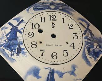 Delft Blue Windmill Clock Face — This vintage Delft blue clock face features classic Dutch scenes with windmills and sailing boats in traditional blue and white colors. The dial is marked 'EIGHT DAYS' and 'MADE IN U.S.A', with three winding holes indicating a mechanical clock movement. Measuring approximately 9.5 inches wide, this decorative piece is designed for an eight-day clock but currently lacks hands and mechanism. The condition shows minor age-appropriate wear with no visible cracks or chips. A charming collectible accent for clock restoration or Dutch-themed decor.