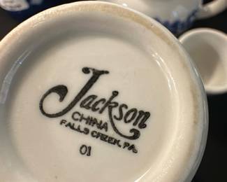 Jackson China Blue Floral Teapot Set — This charming Jackson China teapot set from Falls Creek, PA, features classic blue floral designs on white ceramic. The set includes a compact teapot with lid and two matching cups, all decorated with delicate blue floral motifs. The teapot measures approximately 4.5 inches in height and 8 inches in length including the handle and spout, with cups around 2.5 inches tall and 3 inches wide. The set is in good condition, showing minor usage wear with no chips or cracks visible. This vintage ceramic set is perfect for collectors or for adding a quaint touch to any kitchen or dining room.