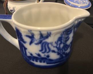 Doulton Blue White Pitcher England — This charming Doulton pitcher from England features a classic blue and white design, characteristic of traditional Doulton ceramics. The pitcher displays intricate blue patterns on a white background, including detailed foliage and landscape motifs. It measures approximately 5 inches tall and 5.5 inches wide, making it a practical and decorative piece for kitchen or dining use. In very good condition, the pitcher shows no visible chips or cracks, with a well-preserved glaze. Marked on the bottom with the Doulton maker's mark and 'Made in England', this piece reflects authentic English craftsmanship.