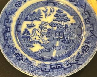 Doulton's Blue Willow Dinner Plate — This charming Doulton's Blue Willow dinner plate showcases the classic blue and white willow pattern that has been beloved for generations. Crafted from fine ceramic, the plate features intricate scenic designs including pagodas, boats, and bridges framed by geometric and floral borders. Measuring approximately 10 inches in diameter, it serves as both a functional dish and a collectible decorative item. The plate is in good condition with minor surface wear typical of vintage use but no visible chips or cracks. Doulton's hallmark indicates quality craftsmanship synonymous with English pottery traditions.