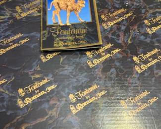 Fontanini by Roman, Inc Box — Fontanini box from Roman, Inc. featuring gold logo print and camel artwork on a marbled dark blue background; marked "Fontanini exclusively from Roman, Inc." on the lid. Cardboard storage/packaging box likely for Fontanini nativity/figure collectibles, with decorative printed exterior and small scuffing at corners. Dimensions are estimated and suitable for tabletop collectibles storage. Good used condition with light shelf wear and a tear at one corner; box appears structurally sound but shows cosmetic wear.