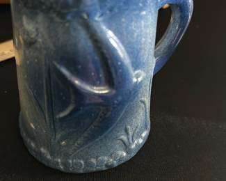 Blue Stoneware Mini Mug — This charming blue stoneware mini mug features a textured floral and leaf relief design that adds a rustic and handcrafted appeal. The mug is compact and solidly built, perfect as a decorative piece or for serving small beverages or a test cup. Its rich blue glaze complements the intricate detailing and gives it an artisanal feel. The mug is in good condition with minor surface imperfections consistent with handcrafted pottery. Ideal for collectors of handmade ceramics or as a unique accent piece in gift shelves or kitchen displays.