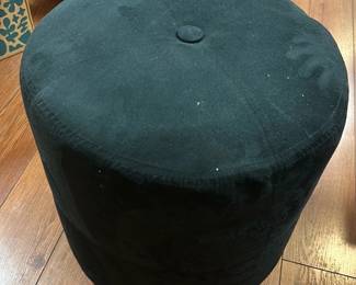 Black Velvet Round Ottoman — This black velvet round ottoman offers a plush and versatile seating or footrest option. It features a smooth, soft velvet upholstery with a central button tuft for subtle detailing. The ottoman measures approximately 18 inches in height and 16 inches in diameter, making it compact and easy to place in any living space. In good condition with minor signs of wear consistent with light use. Its simple cylindrical design complements various decor styles, ideal for basement or living room settings.
