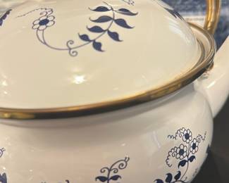 Blue Danube White and Blue Teapot — This charming Blue Danube teapot features classic white porcelain adorned with delicate blue floral patterns and a brass-colored lid handle. It includes a black wooden handle with brass accents, blending function with traditional style. The teapot measures approximately 5.5 inches in height, 6.5 inches in width, and 9 inches in length, making it a practical yet elegant addition to any tea set or display. The teapot is in good condition with minor wear visible on the base typical of vintage porcelain items. Marked clearly on the bottom with the Blue Danube logo, this piece represents classic mid-20th century design.