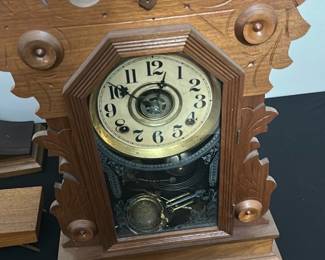 Vintage Oak Mantel Clock with Carved Det — This vintage oak mantel clock features intricate carved leaf and floral designs on the frame, highlighting fine craftsmanship. The clock face has a cream dial with black Arabic numerals and visible brass clockwork through the glass door. The detailed pendulum and etched glass panel add to the clock’s ornate Victorian-style charm. Measuring approximately 16 inches tall by 10 inches wide, it is a striking decorative and functional piece. It is in good condition with minor wear consistent with age and appears to be fully intact but unverified for working condition.