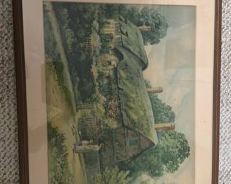 Framed Cottage Watercolor Print — Framed watercolor-style print depicting an English cottage with thatched roof, garden, and a small statue in the foreground. Housed in a simple brown wood frame with off-white matting; artwork appears to be a reproduction print rather than an original painting. Frame measures approximately 26 inches wide by 20 inches tall and is lightweight enough for wall display. Glass has minor surface scratches and mat shows light age-toning, overall in good condition for resale at an estate sale.
