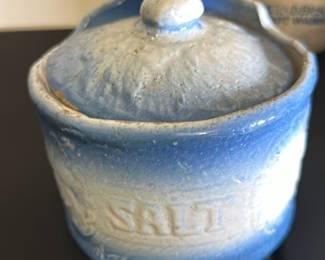 Vintage Blue Salt Crock Pottery — This vintage salt crock features a charming blue and cream glaze finish with embossed salt lettering on the front. Made from ceramic pottery, it includes a fitted lid with a small handle, ideal for kitchen or collectible display. Measuring approximately 4 inches high and 4 inches wide, this piece adds rustic charm to any collection or kitchen counter. It is in good condition with some aging visible in the glaze and minor imperfections consistent with vintage ceramics. A lovely rustic and functional collectible that suits a variety of decor styles.