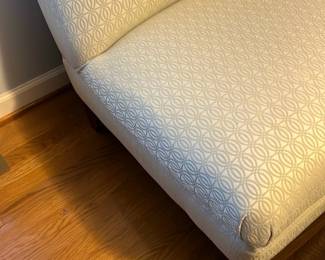 Upholstered Slipper Chair & Ottoman — Armless slipper chair with matching ottoman upholstered in a light cream geometric patterned fabric. Clean lines and low profile make this set suitable for a bedroom or sitting area; hardwood block legs provide a sturdy base. Overall dimensions listed below are estimated for practical staging and moving considerations. In good condition with light, even wear to upholstery and no visible stains or tears.