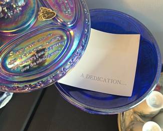 Fenton Blue Carnival Glass Eagle Covered — This striking Fenton covered dish features iridescent blue carnival glass with an eagle finial on top. The lid is embossed with inspirational text and the iconic Fenton sticker is present, confirming authenticity. The piece stands approximately 9 inches tall and 7 inches wide, making it an eye-catching collectible centerpiece. The dish is in excellent condition with vibrant coloration and no chips or cracks. A rare Fenton collectible, perfect for carnival glass enthusiasts or patriotic decor collectors.