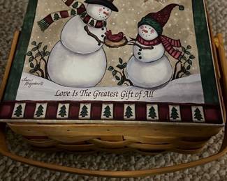 Snowman Ornament Basket — Decorative basket set with hand-painted snowman Christmas ornaments; perfect for holiday display or gifting. The woven wood basket contains multiple carved-style snowman ornaments with painted details, scarves, hats, and hanging loops — top of lid reads "Love Is The Greatest Gift of All." Compact and lightweight for easy storage and seasonal use. Measurements are approximate; ornaments show light shelf wear consistent with prior use but no major damage visible. Seller notes: Item Location: Bonus Up Room.