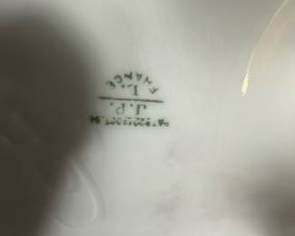 JP Vase Paris Porcelain Chocolate Pot — This delicate chocolate pot from JP Vase Paris is a beautifully crafted porcelain piece featuring elegant floral hand-painted designs in soft purples and greens. The pot has a gracefully curved form with ornate gold trim on the lid, spout, and handle, reflecting a refined vintage aesthetic. It measures approximately 7.5 inches in height, 5 inches in width, and 4.5 inches in length, making it a charming addition to any bedroom or display. The pot is in good vintage condition with minor signs of wear and no visible chips or cracks. This collectible porcelain piece bears a clear JP Vase Paris mark on the bottom, attesting to its authenticity and quality.