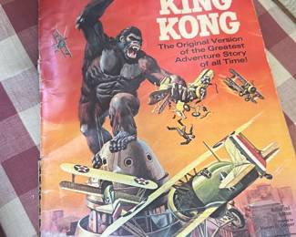 Giant Classic King Kong Comic — Giant Classic King Kong paperback comic featuring dramatic painted cover art of Kong battling vintage aircraft. Softcover pulp-style publication with wear along spine and edges, creased corners, and slight cover scuffing consistent with age. Measures approximately 11.5 inches tall x 8.5 inches wide and is lightweight and easy to mail; good for collectors of film memorabilia or retro comics. Overall condition: fair with visible shelf wear but intact binding; pages appear complete though not inspected individually.