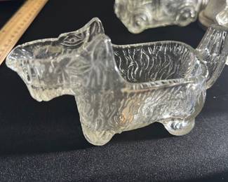 Vintage Clear Glass Dog Candy Dish — This charming vintage clear glass candy dish is designed in the shape of a dog, featuring textured detailing that mimics fur. The piece measures approximately 5 inches in length, 2.5 inches in width, and 2.5 inches in height, making it a perfect small decorative item or desk accessory. Crafted from thick glass, it offers a sturdy feel and a whimsical touch suitable for collectors or as a unique gift. The item is in good condition with no visible chips or cracks, preserving its nostalgic appeal. A delightful collectible from a past era, ideal for adding character to any space.