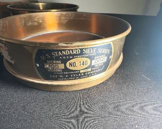 U.S. Standard Sieve No. 140 — This vintage U.S. Standard Sieve No. 140 is part of the W.S. Tyler Company's sieve series, renowned for precise particle size classification. Made of metal, this sieve features openings sized at .005 microns and .0041 inches, useful for laboratory or industrial use. Measuring approximately 6 inches in diameter and 2 inches in height, it is sturdy yet lightweight. The sieve shows signs of patina and wear consistent with age but remains structurally sound and functional. A collectible piece reflecting early 20th-century industrial design and manufacturing from Cleveland, Ohio.