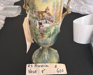RS Prussia 8in Hand-Painted Vase — This exquisite RS Prussia vase features a delicate hand-painted pastoral scene with a thatched cottage and garden, accented by ornate gold handles and trim. The vase displays a soft blend of pastel greens and blues, enhancing its vintage charm and collectible appeal. Measuring 8 inches tall, this elegant piece is perfect for display in a bonus up room or any refined setting. It is in excellent condition with no visible chips or cracks and retains its original vibrant finish. RS Prussia pieces are renowned for their craftsmanship and artistry from the late 19th to early 20th century.