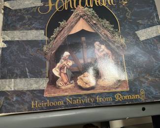 Roman Heirloom Nativity Set — Heirloom nativity set from Roman in original labeled box, featuring a small bark-style stable and hand-painted resin or composite figures (wrapped in protective plastic). Stable measures compactly for tabletop display; figures include baby Jesus, Mary and Joseph stored inside the stable. Good estate-condition with light shelf wear to box and stable; figures appear intact though sale as-is since packaged in plastic. Great seasonal decoration for a mantel or holiday display.
