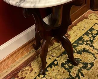 Marble Top Mahogany Table — This Victorian mahogany side table features a stunning round white marble top with gray veining, adding elegance and durability. The intricately carved tripod base showcases classic Victorian craftsmanship and rich mahogany wood construction. Measuring approximately 27 inches tall with a 20-inch diameter top, it fits perfectly as an accent or occasional table in your front room. The piece is in good condition with minor surface wear on the wood base consistent with age. Its timeless style and quality materials make it a prized addition to any traditional home decor.