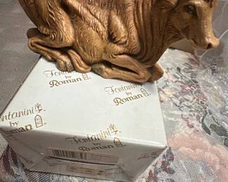 Fontanini Roman Nativity Ox — This Fontanini by Roman nativity ox figure is a detailed resin/painted piece from the popular Fontanini nativity line. The figure is painted a warm brown with textured fur detailing and lifelike eyes; it comes with the original Fontanini by Roman box labeled item #52834 and a Dillard's price sticker. Measuring approximately 4.5 inches tall, 8.5 inches long and 3.5 inches deep, it's a compact, display-ready piece for holiday scenes or shelf decor. Overall in good condition with light shelf wear to paint consistent with normal display; box shows retail stickers and light age wear.