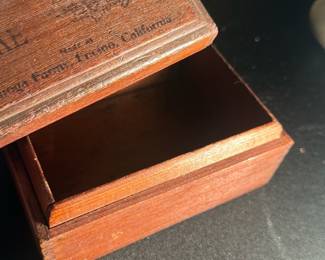 Nectar Cake Wooden Advertising Box — This vintage wooden advertising box features the inscription "Nectar All Fruit Cake" and branding from Carnegie Flavor Process, California. The small rectangular box is crafted from stained wood with dovetail joints and a hinged lid, perfect for display or storage of small items. The box measures approximately 3.5 inches in width, 2.5 inches in depth, and 2 inches in height, making it a compact collectible piece. It is in good condition with minor wear consistent with age, including some fading on the printed text and slight surface marks. A charming early 20th-century advertising collectible, ideal for nostalgia collectors or display in a vintage-themed setting.
