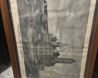 Union Station Nashville Print — Framed lithographic print depicting Union Station, Nashville, Tennessee (terminals of the Nashville, Chattanooga & St. Louis Railway). The piece is matted and set in a simple oak-tone wooden frame with glass, showing architectural detail of the historic station in grayscale. Overall size is moderate and suitable for wall display in a bonus room or office; frame shows light surface wear and the paper has mild age-toning and a small crease near the top edge. Good estate-sale condition for display with no major tears to the image; glass and frame are intact though the frame has minor scuffs consistent with normal use.