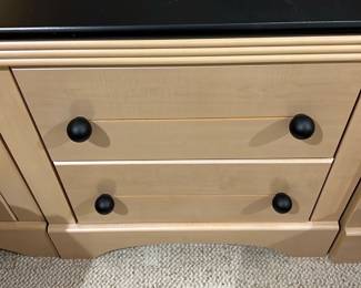 2-Drawer Nightstand Black Top — This elegant nightstand features a natural maple wood finish complemented by a contrasting black top surface. It is designed with two drawers, each fitted with simple black round knobs, providing practical storage for bedroom essentials. The piece measures approximately 24 inches in height, 24 inches in width, and 16 inches in depth, making it a compact addition ideal for a variety of bedroom styles. The condition is good with minor surface scratches on the top, consistent with normal use. Its classic and versatile design suits both traditional and modern bedroom decor.