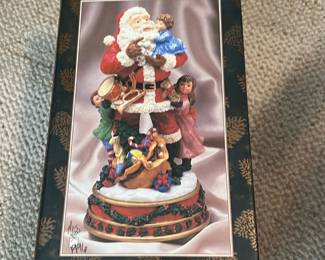Musical Santa Figure — Musical Santa collectible in original box; pictured as a classic Santa with children and toy sack on a decorative base. Boxed holiday figurine plays a tune (label: "Musical Santa") and is intended for display during the Christmas season; seller notes location: Office Up Room. Measurements are estimates for boxed figurine and suitable for shelf display. Item appears in good condition with original packaging showing light shelf wear; music function not tested.