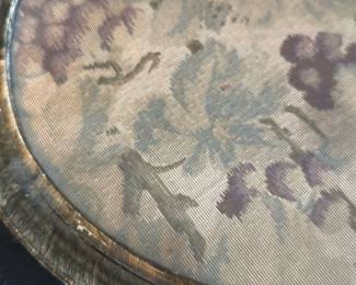 Vintage Metal Tray with Fabric Insert — This vintage metal tray features a round design with a fabric insert displaying a delicate grapevine pattern in muted purple and green tones. The tray has two handles for easy carrying and exhibits a rustic patina that enhances its antique charm. Measuring approximately 17 inches in diameter with a shallow depth, it is an excellent decorative or serving piece. The tray shows signs of wear consistent with age but remains structurally sound. Ideal for vintage collectors or as a unique home decor accent.