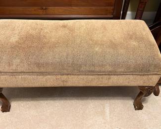 Carved Wood Storage Bench — This carved wood storage bench combines functional seating with elegant design. Upholstered in a beige fabric, it features detailed claw feet and carved legs reminiscent of classic styles. The bench measures approximately 19 inches tall, 42 inches wide, and 16.5 inches deep, providing comfortable seating and hidden storage inside. It is in good condition with slight wear on the upholstery consistent with normal use. A versatile piece suitable for bedroom seating or hallway storage.