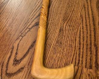 Hand-Carved Wooden Cane — This hand-carved wooden cane features intricate detailed patterns along its shaft, showcasing skilled craftsmanship. Made from light-colored wood, it has a smooth curved handle for comfortable grip. Measuring approximately 36 inches in length, it is a charming and functional walking aid or collectible item. The cane is in good condition with minor wear consistent with gentle use. Its unique carved design makes it a distinctive accessory or decorative piece.