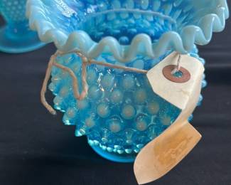 Fenton Blue Opalescent Hobnail Vase — This charming Fenton hobnail vase features a stunning blue opalescent glass with a ruffled edge, characteristic of mid-20th century American art glass. The hobnail pattern enhances its textured beauty and classic collectible appeal. Measuring approximately 4.5 inches in height and 4 inches in width, this vase is perfect for display or small floral arrangements. It is in excellent condition with no chips or cracks visible. A delightful piece for collectors of vintage Fenton glassware.