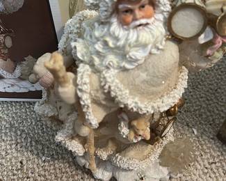 Cedar Creek Holiday Santa Figurine — Cedar Creek Collection holiday Santa figurine in a cream/ivory finish with textured flocking and painted face. The figure carries a sack of toys and staff and includes detailed accents like tiny teddy and drum; boxed with original Cedar Creek Collection holiday box. Measures approximately 12 inches tall by 6 inches wide and 6 inches deep, a good tabletop holiday decor size. Overall good condition with light surface wear to flocking and some cardboard wear to the original box; no major chips or breaks visible.