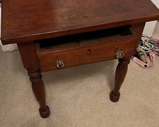 Vintage Wood Side Table with Drawer — This vintage wooden side table features a rich, warm finish and a single drawer with two glass knobs for convenient storage. Crafted with sturdy turned legs and a solid wood top, it adds classic charm to any bedroom or living area. The table measures approximately 25 in height, 26 in width, and 18 in depth, making it a versatile piece for small spaces. It shows signs of age-related wear, including surface scratches and minor stains, but remains structurally sound. A timeless addition for those seeking functional vintage furniture.