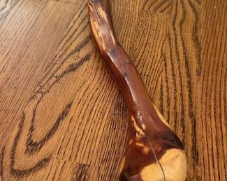 Hand-Carved Wooden Walking Stick — This hand-carved wooden walking stick features a natural, rustic design with a rounded handle and smooth finish. Crafted from solid wood, it offers durability and a comfortable grip for everyday use or hiking. Measuring approximately 36 inches in length, it is lightweight yet sturdy. The walking stick is in good condition with minor surface cracks that add to its character without compromising functionality. Its natural wood grain makes it a unique and practical accessory for outdoor enthusiasts or collectors of rustic gear.