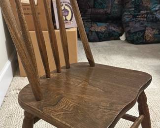 Child Wooden Chair Brown Finish — This child-sized wooden chair features a classic arched back with vertical slats, finished in a warm brown tone perfect for bedroom use. The sturdy construction includes turned legs and stretchers for added stability and durability. Measuring approximately 18 in height, 13.5 in width, and 14 in depth, it is well-suited as a child’s chair in a bedroom up room setting. The piece is in good condition with minor signs of use, consistent with a child's furniture. Its simple design and solid wood material make it a functional and charming addition to any child's bedroom.