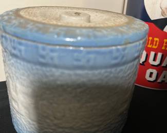 Blue Crock butter Covered Jar — This blue ceramic covered jar features a textured surface and a snug fitting lid with a small knob handle. The jar showcases a gradient blue glaze that fades from a deeper blue at the rim to a pale finish toward the base, giving it a charming handcrafted appearance. Measuring approximately 4 inches in height and 4.5 inches in diameter, it is suitable for decorative storage or accent display in the bonus up room. The piece is in good condition with no visible chips or cracks and retains its original glaze and structure. Its simple yet rustic design makes it a versatile home decor piece.