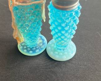 Blue Hobnail Glass Salt & Pepper Shakers — These charming blue hobnail glass salt and pepper shakers feature a distinctive textured pattern with shiny metal tops. The bright blue color and vintage style make them a delightful addition to any table setting or collection. Each shaker stands approximately 4.5 inches tall with a sturdy round base for stability. They are in good vintage condition with minor surface wear consistent with age and use. Ideal for collectors or those looking to add nostalgic flair to their kitchen decor.