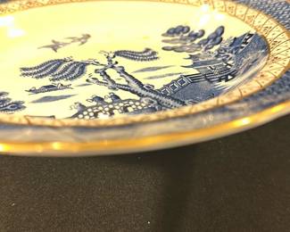 Blue Willow real old willow  Plate — This charming Soothe 'Real Old Willow' scalloped plate from England showcases classic blue and white Willow pattern imagery with gold trim. Crafted from fine ceramic, it features a detailed bridge, willow tree, and pagoda scene in blue hues against a white base accented by an intricate border design. The plate measures approximately 9.5 inches in diameter, making it suitable for display or dining use. It is in good condition with minor surface discoloration noted but no chips or cracks visible. A lovely example of traditional English transferware from a respected maker.
