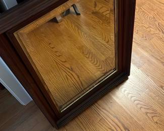 Dark Brown Wood Framed Mirror — This dark brown wood framed mirror features a classic paneled design that adds elegance to any living room or hallway. The sturdy wooden frame has a rich finish that complements various decor styles, making it a versatile accent piece. Measuring approximately 32 inches tall by 24 inches wide, it is ideal for mounting on walls or resting against furniture. The mirror is in good condition with minor signs of wear consistent with regular use. Its timeless style and quality craftsmanship make it a functional and decorative addition to your home.