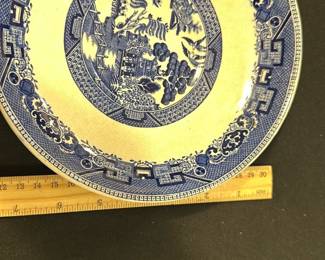 Buffalo Pottery Blue Willow Plate — This distinctive Buffalo Pottery Blue Willow plate features classic blue and white transferware design with intricate scenic patterns typical of the Blue Willow style. Made from semi-vitreous china, it presents an elegant and durable form with visible crazing that adds vintage character. The plate measures approximately 10.25 inches in diameter, ideal for display or dining use. It is in good vintage condition with minor staining and typical wear from age, consistent with the semi-vitreous finish. Buffalo Pottery was a prominent manufacturer known for quality American ceramics in the early 20th century, making this plate a collectible piece.