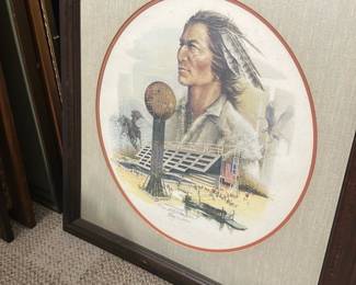 Signed Native Portrait Limited Print — Limited-edition lithograph featuring a Native American portrait with the Sunsphere and Tennessee World's Fair pavilion imagery, signed and dated May 1, 1982. The print is matted in a round opening with a linen-style mat and set in a dark wood frame; artist signature and edition number (e.g., 67/100) visible near the lower image. Overall framed piece is moderately large and suitable for a den or bonus room display. Condition is good with light surface wear to the mat and frame and no obvious tears to the print; glass appears intact but may have minor scuffs.