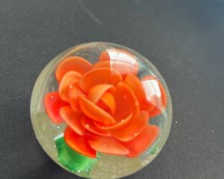 Red Rose Glass Paperweight — This charming glass paperweight features a vibrant red rose encapsulated within a clear spherical form. The intricate petals and green stem are skillfully crafted, showcasing a delicate and colorful floral design. Measuring approximately 3 inches in diameter, it is a lovely decorative accent suitable for any desk or display shelf. The piece is in good condition with no visible chips or cracks. Perfect for collectors of glass art or as a thoughtful gift item.