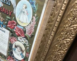 God Bless Our Baby Framed Record — Charming framed "God Bless Our Baby" baby record with colorful Victorian-style illustrations and floral borders. The piece features a printed baby's record center with spaces filled in by hand and is set in an ornate gold-toned molded frame. Frame measures approximately 24 inches high by 18 inches wide and is a lightweight decorative piece suitable for nursery or wall display. Condition is good for age with light wear to frame gilt and minor foxing/toning to the paper; glass appears intact.