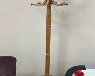 Wooden Bentwood Coat Rack — This classic wooden bentwood coat rack offers both style and function with its curved arms and sturdy support. Crafted from solid wood with a natural finish, it features multiple hooks at the top and a circular base designed for stability. Standing approximately 68 inches tall, it fits perfectly in a basement room or entryway for hanging coats, hats, and scarves. The coat rack is in good condition with minor signs of wear consistent with age and use. Its timeless design makes it a versatile piece for various decor styles.