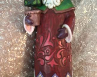 Jim Shore Holiday Trim Santa — This Jim Shore 'Holiday Trim' Santa figurine from the Jim Shore Heartwood Creek line is a colorful resin holiday collectible. Hand-painted with a patterned red robe, green collar, white beard and decorative base, it carries a topiary tree and stands on a blue plinth. Small tabletop figurine ideal for holiday display in an office or mantel; exact dimensions estimated below. Good condition with original felt pads on the base and no visible chips or cracks; licensed by Enesco and made in China per base label.