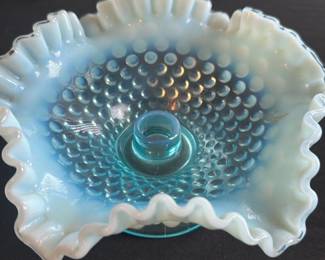 Fenton Blue Opalescent Hobnail Candlehol — This charming Fenton blue opalescent hobnail candleholder features a ruffled edge with a hobnail pattern on the bowl and a sturdy pedestal base. The blue glass with opaline white edge adds a delicate vintage look perfect for decorative settings. Measuring approximately 4.5 inches in height and 7 inches in diameter, it is a versatile accent piece for any room. The candleholder is in good vintage condition with slight wear consistent with age and use. A classic collectible from Fenton, this piece showcases the brand's signature artistry and glass craftsmanship.