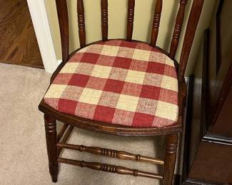 Wooden Chair with Red Checkered Seat — This classic wooden chair features a rounded spindle back and a red and beige checkered fabric seat cushion. The chair’s rich wood finish complements the traditional design, making it a charming addition to any bedroom or dining space. Measurements approximate 37 inches in height, 18 inches in width, and 17 inches in depth, providing comfortable seating. The chair is in good condition with minor signs of wear consistent with age but remains sturdy and functional. Its timeless style and durable construction enhance its practical use and aesthetic appeal.