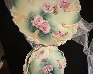 6 pc RS Prussia Handpainted Bowl Set — This beautiful RS Prussia bowl set features handpainted pink roses on a soft green and cream background with ornate scalloped edges. The set includes a large bowl and several smaller matching bowls, each showing delicate floral detail and gold trim. The large bowl measures approximately 12 in in diameter and the smaller bowls about 7 in. These pieces are in good condition with minor wear consistent with their age, showcasing elegant late 19th to early 20th-century porcelain craftsmanship. A charming addition to any vintage ceramic or china collection.
